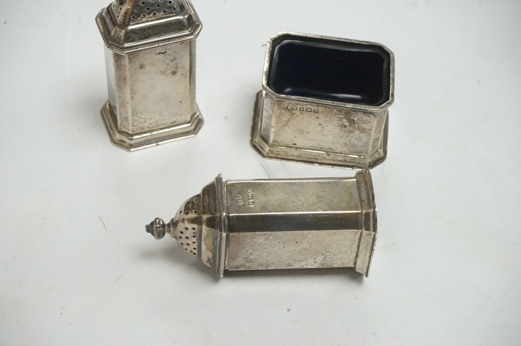 A George V silver four piece condiment set, by Elkington & Co, Birmingham, 1935, pepper height 70mm, with two blue glass liners. Condiment - fair to good